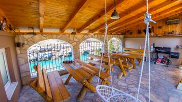 Un intérieur rustique avec des murs en pierre, des bancs en bois et un luminaire suspendu.