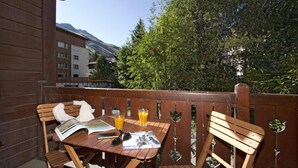 En træterrasse med et bord, stole, en bog og to glas appelsinjuice.