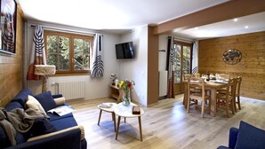 En hyggelig stue med sofa, sofabord og spiseplads med bord og stole.