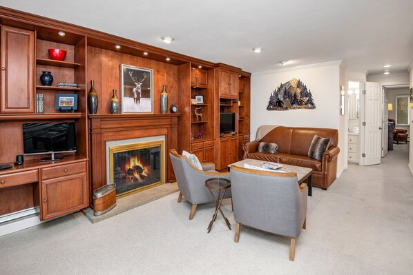 A living room with a fireplace, wooden cabinets, a television, and a leather sofa.
