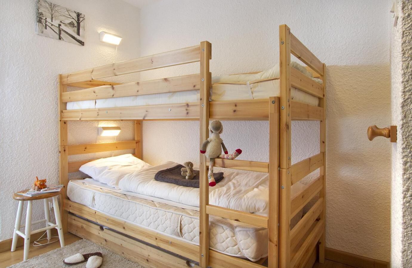 A bunk bed room with a small table and a plush toy on the top bunk.