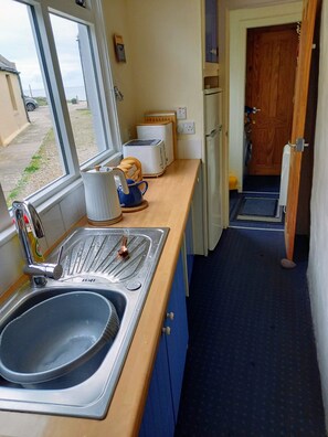 Eine kleine Küche mit Spüle, Toaster und Blick ins Freie.