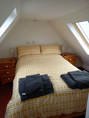 Ein Schlafzimmer mit einem Bett, zwei Nachttischen und einem Fenster.