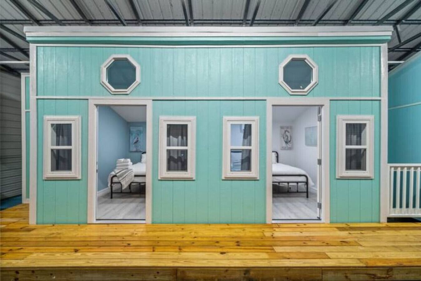 A two-room cabin with a wooden floor, each room featuring a single bed and a window.