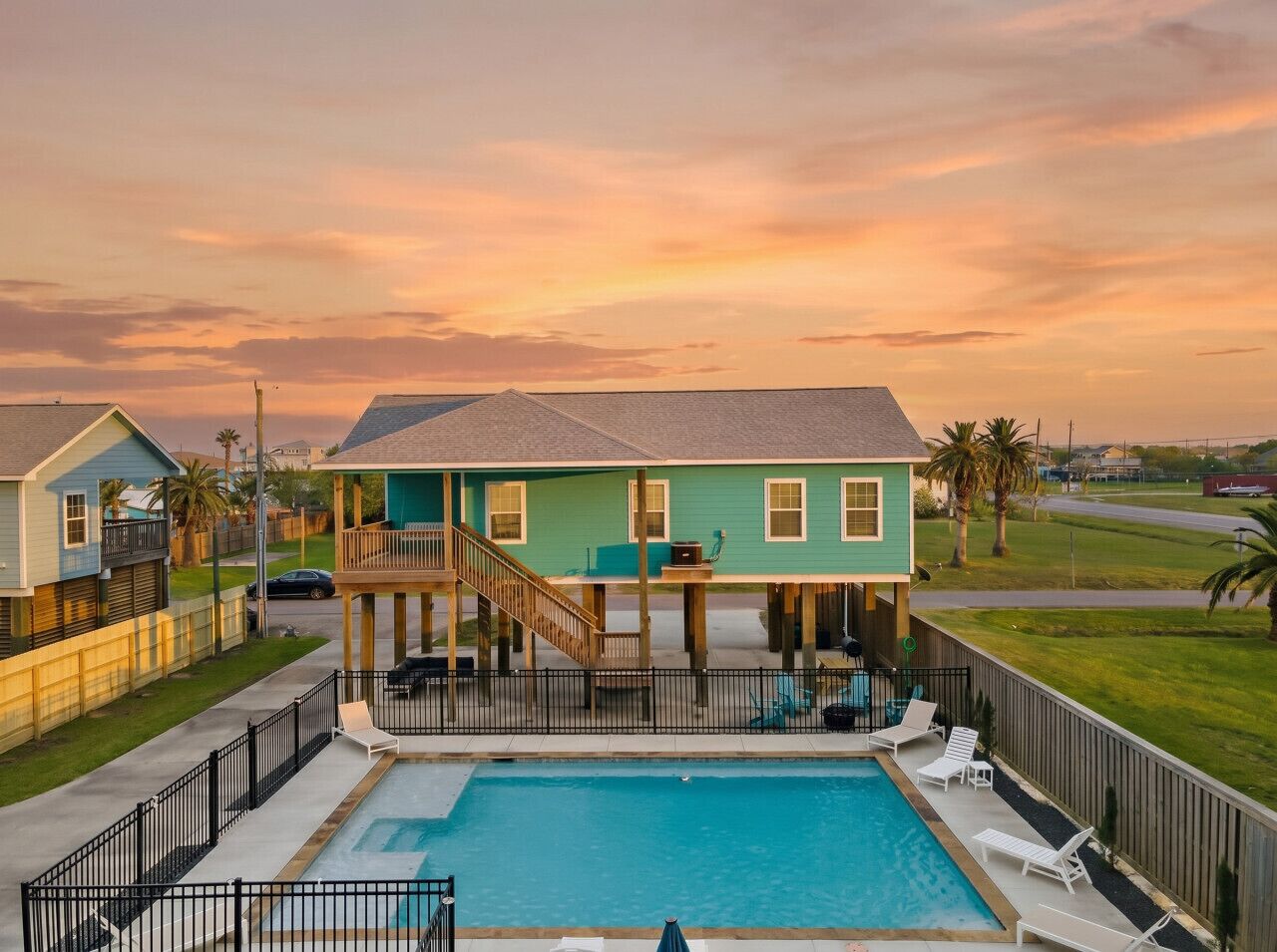 A two-story house with a pool, a covered deck, and a fenced backyard.