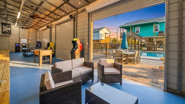 An indoor recreational area with a pool, outdoor seating, and a view of a house. - Stunning Home with Expansive Pool & Game Room (Kemah Area)