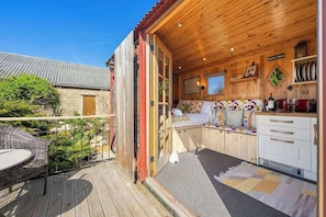 Une cabane en bois dotée d’un balcon, d’un coin repas et d’une cuisine.