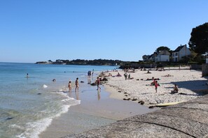 A beach with people sunbathing and swimming, a rocky shoreline, and houses in the background. - "Les Flots" - Sleeps 10 - Direct beach access - Parking (3 cars) (Saint-Pierre-Quiberon)