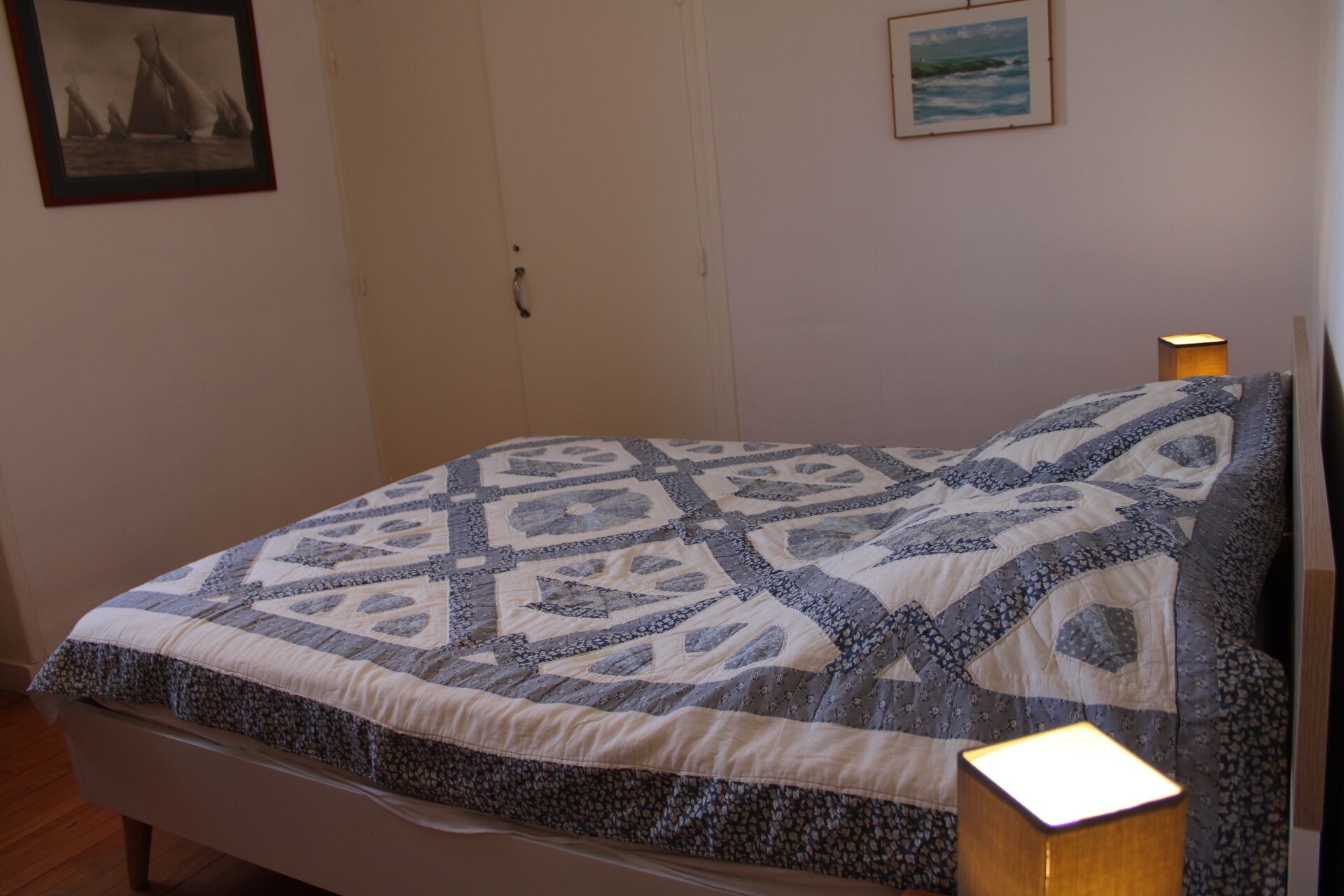Uma cama com um edredom estampado, uma luminária de cabeceira e duas fotos emolduradas na parede.