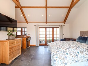 A bedroom with a bed, dresser, desk, and a large window.