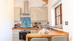 A kitchen with a wooden countertop, a stove, cabinets, and a window. - Rosewarrick Cottage (Bodmin)