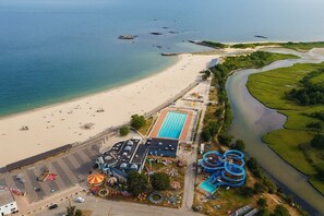 An aerial view of a beach resort with a swimming pool, water slides, and a parking area. - Luxury 8BR Winter Wonderland • Sleeps 22 • Indoor Fireplaces & Ocean Views (New London)