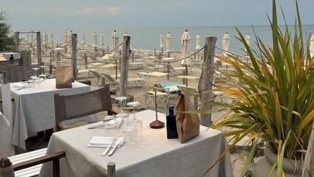 Un espace de restauration en plein air avec des tables disposées pour deux personnes, donnant sur une plage.