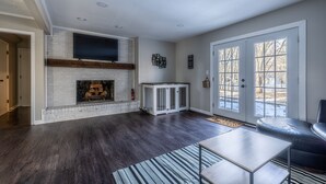 A spacious living room with a fireplace, a large TV, and a sliding glass door leading to a patio.