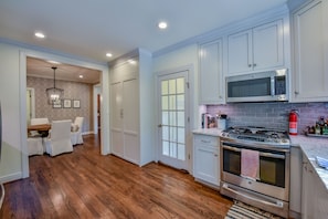 Enjoy cooking in this well-equipped kitchen with a stainless steel range hood, microwave, and white cabinetry.