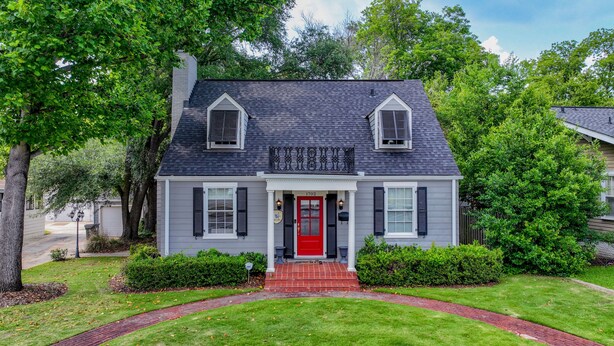 A two-story house with a red front door, white shutters, and a black roof.
