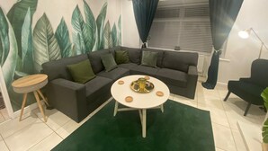 A modern living room with a sectional sofa, a round coffee table, and a green rug. - Charming 3-bed House Near Central Manchester (Manchester)