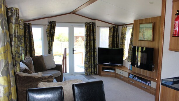 A living room with a sofa, TV, and wooden entertainment unit.