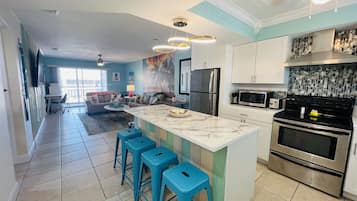 A modern kitchen with a central island, stainless steel appliances, and a dining area with blue stools.