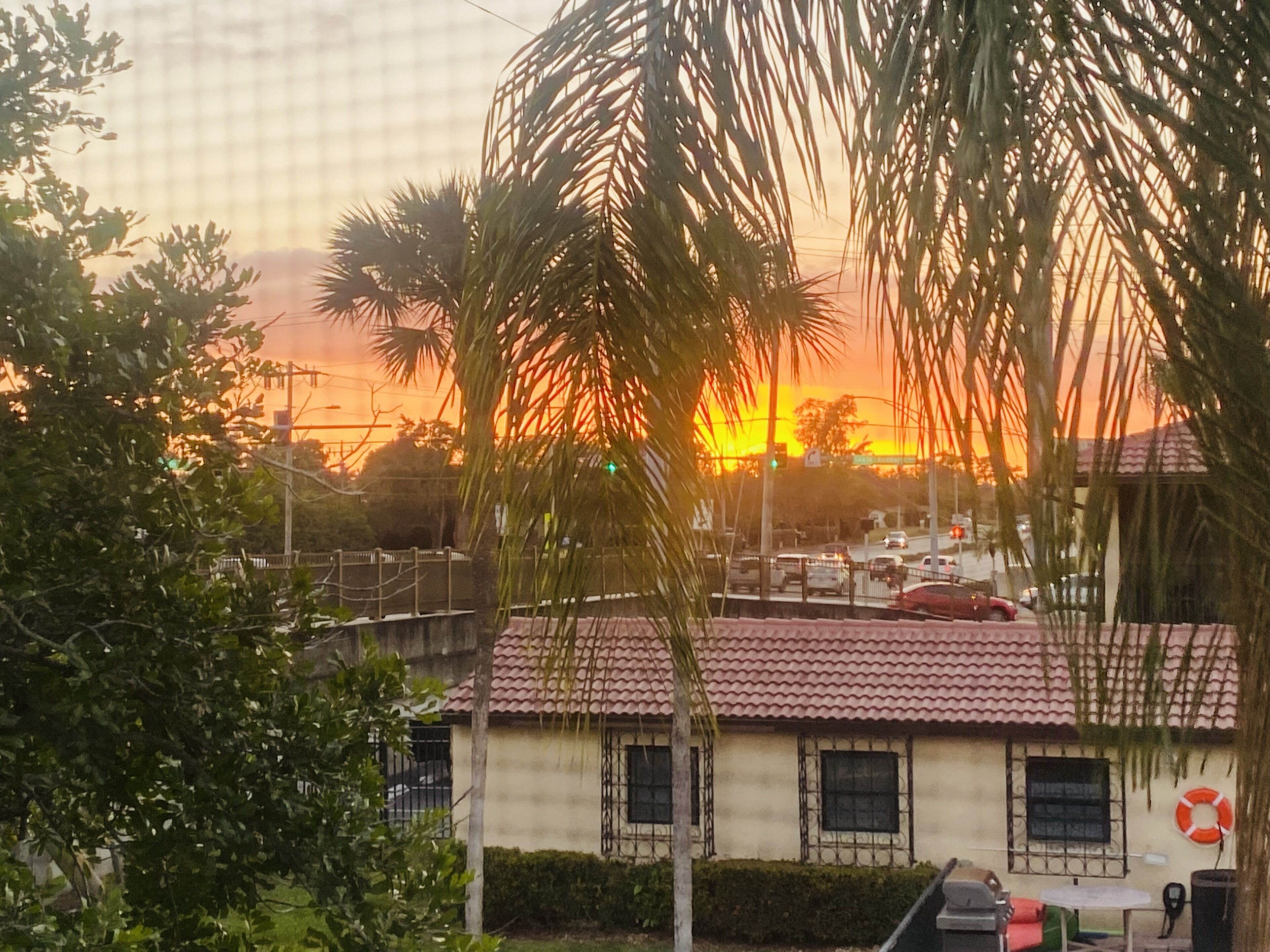 Un bâtiment avec un toit recouvert de tuiles rouges, une bouée de sauvetage accrochée au mur et une vue sur le coucher de soleil.