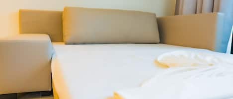 A neatly made bed with a white comforter and a folded blanket on the side.