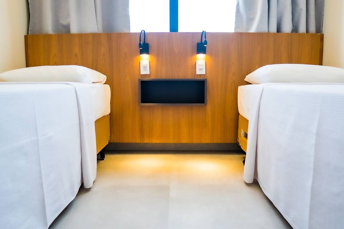 A hotel room with two beds, a wooden headboard, a flat-screen TV, and bedside lamps.