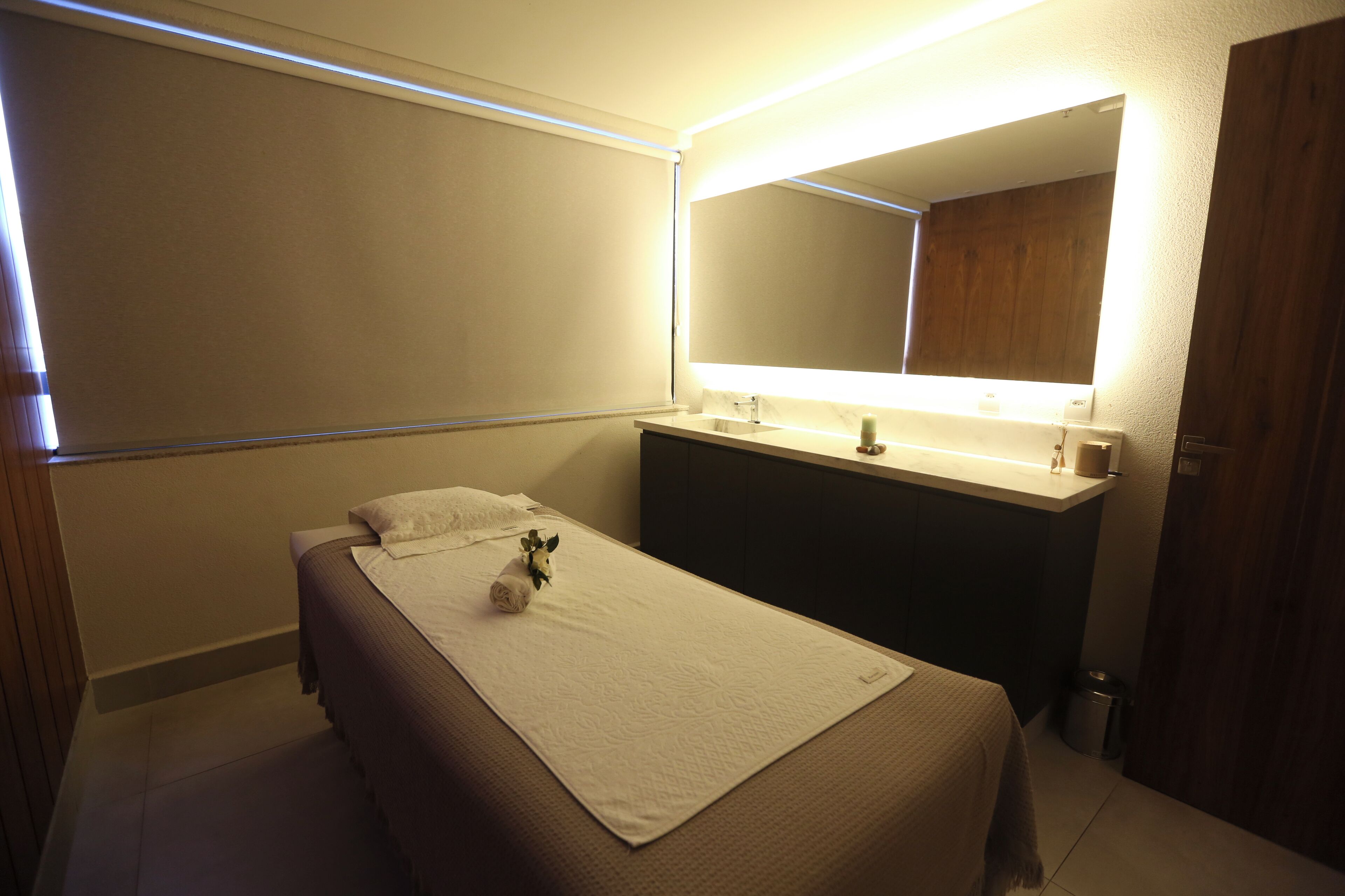 Ein Hotelzimmer mit einem Bett, einem Nachttisch, einem Spiegel und einer kleinen Mülltonne.