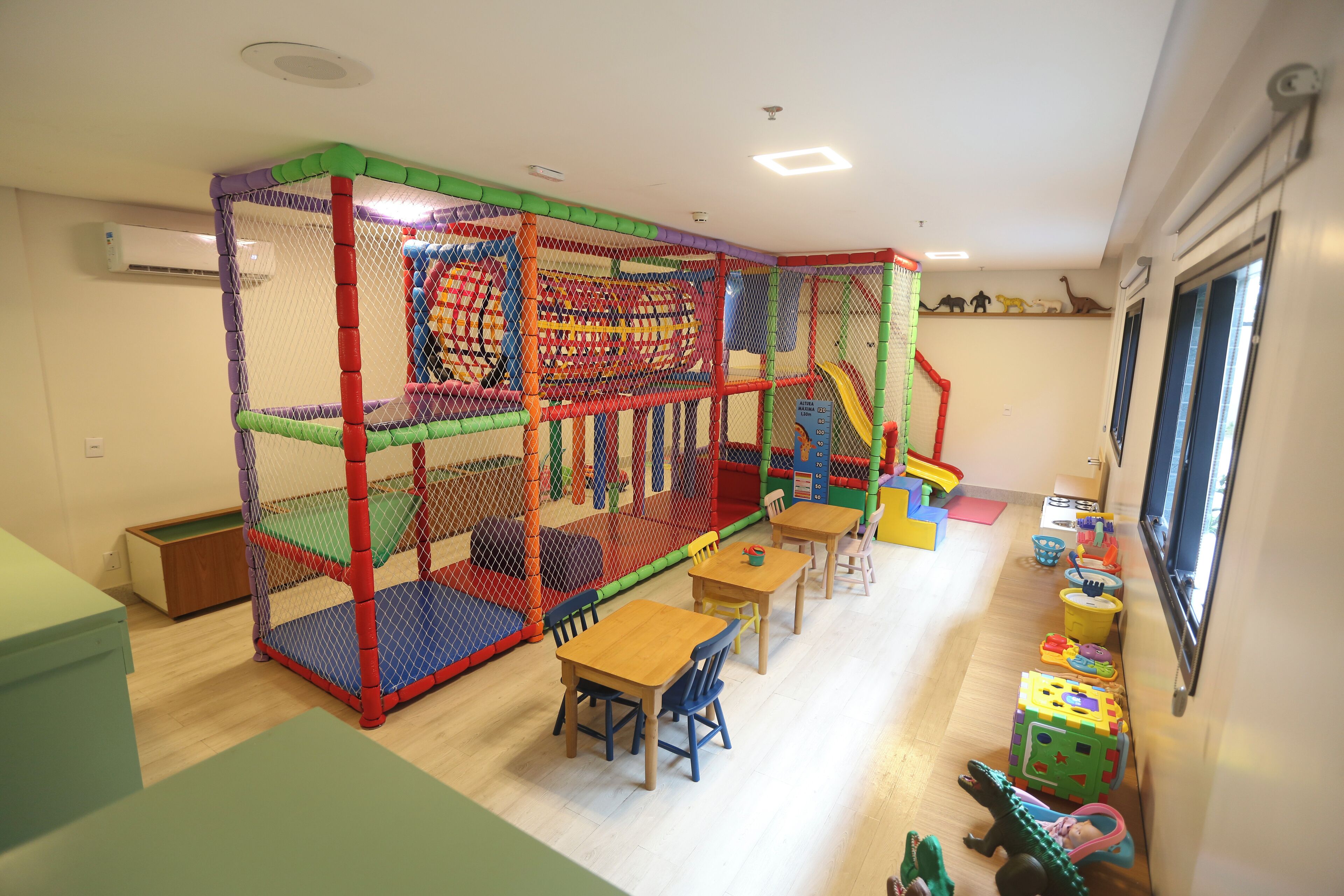 A play area with a netted enclosure, tables, chairs, and toys.