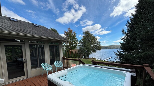 A hot tub on a deck with a view of a lake and trees. - “The Lake house” Private BEACH; SLEEPS 16!!! (Schroon Lake)