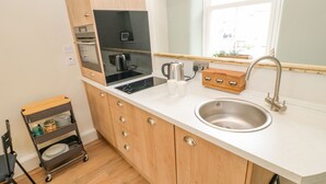 Une cuisine compacte équipée d’une cuisinière intégrée, d’un évier et d’un petit placard.