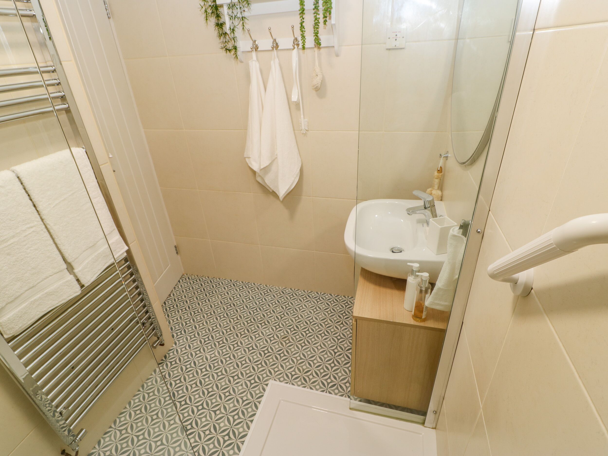 A bathroom with a patterned floor, a white sink, and a towel rack with multiple towels.