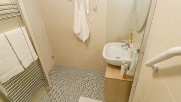A bathroom with a patterned floor, a white sink, and a towel rack with multiple towels.