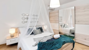 Une chambre à coucher moderne avec un lit à baldaquin, une table de chevet, une lampe et des éléments de décoration murale.