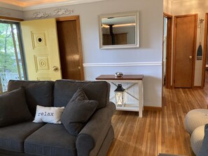 A living room with a sofa, a console table, a mirror, and a door.