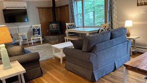 A cozy living room with a fireplace, comfortable seating, and a television. - Cozy Lakeview Family Cottage - steps to the lake, 2 swim docks & restaurant! (Hawley)