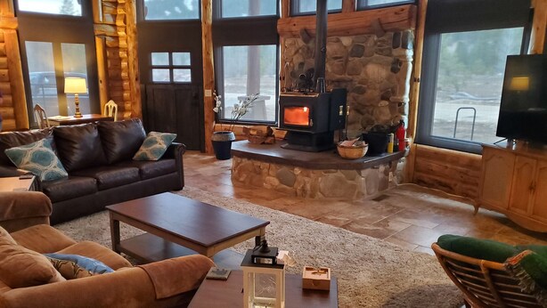 A cozy living room with a stone fireplace, leather sofa, and a television.