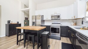 Una cocina moderna con armarios blancos, electrodomésticos de acero inoxidable y una mesa de comedor de madera.