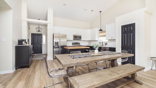 Una cocina moderna con armarios blancos, una mesa de comedor de madera y un horno empotrado.