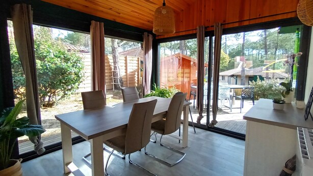 Un espace repas comprenant une table et des chaises, de grandes fenêtres et une vue sur les environs.