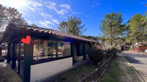 Un petit bâtiment d’un seul étage, avec un toit recouvert de tuiles, de grandes fenêtres et une clôture en bois à l’avant.