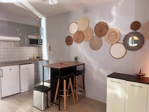 Una cocina moderna con armarios grises, un microondas, un lavabo y una pequeña zona de comedor con taburetes.