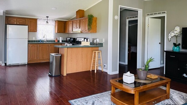 Amplia sala de estar con una mesa de centro de madera, una cocina con armarios de madera y una pequeña isla.
