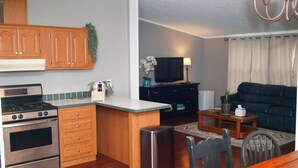 Una cocina moderna con armarios de madera, estufa integrada y comedor con mesa y sillas.
