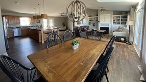 A spacious kitchen with wooden cabinets, a central island, and a dining area with a large wooden table and chairs. - Executive Water View Home With Hot Tub, Just 3 Minutes To Barachois Beach (South Rustico)