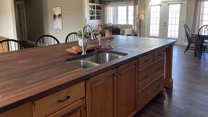A spacious kitchen with a large island, wooden cabinets, and pendant lighting. - Executive Water View Home With Hot Tub, Just 3 Minutes To Barachois Beach (South Rustico)