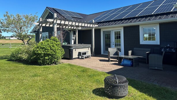 A house with a covered patio, outdoor seating, and solar panels. - Executive Water View Home With Hot Tub, Just 3 Minutes To Barachois Beach (South Rustico)