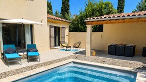A swimming pool with lounge chairs and a covered seating area.