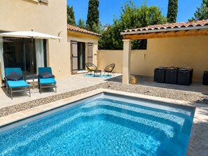 A swimming pool with lounge chairs and a covered seating area.