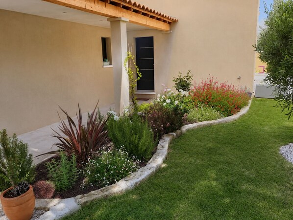A modern house with a well-maintained garden, a wooden pergola, and a door with a window.