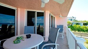 Enjoy ocean views from this balcony with a table and chairs, ceiling fan, and patio access.